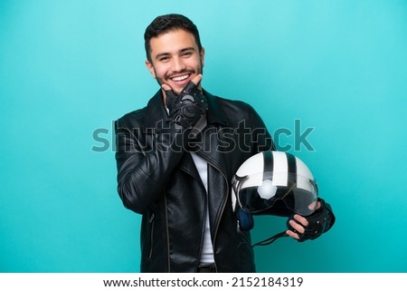 Young Brazilian woman with a motorcycle helmet isolated on blue background happy and smiling