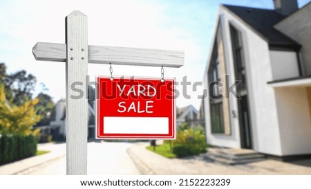 Sign with text YARD SALE and blurred view of modern house