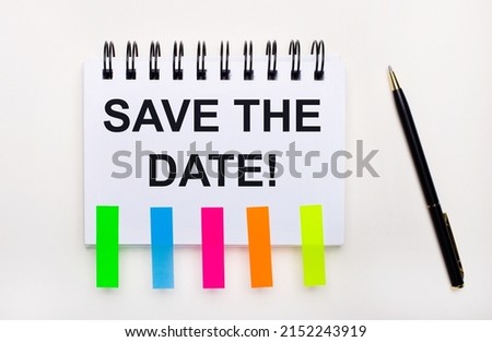 On a light background, a pen, a notebook with the text SAVE THE DATE and bright stickers.