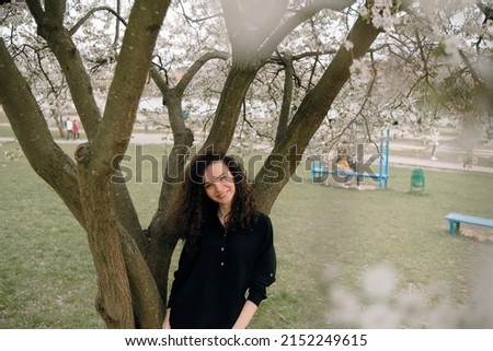 portrait of curly brunette woman in red coat in the park