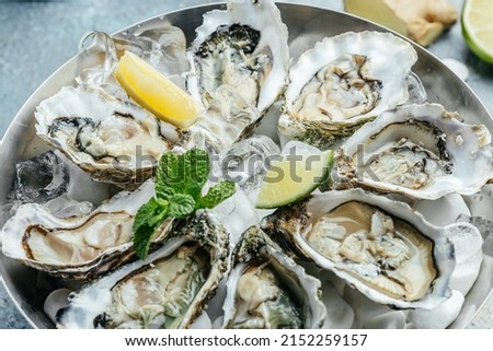 Fresh oysters with lemon and ice. Restaurant delicacy. oysters dish. Oyster dinner with champagne in restaurant, banner, menu, recipe place for text, top view, Royalty-Free Stock Photo #2152259157