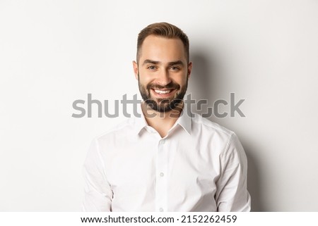 Close-up of confident male employee in white collar shirt smiling at camera, standing self-assured against studio background Royalty-Free Stock Photo #2152262459