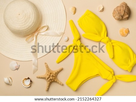 Beautiful yellow bikini and accessories on color background, top view.