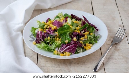 Dietary meal. Healthy lifestyle salad. Fresh mixed salad greens (arugula, radicchio, lettuce, corn and radish) on wooden background. Top view. 