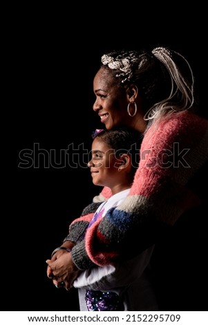  Profile of an African American mother and her young daughter on a black background with a big smile.