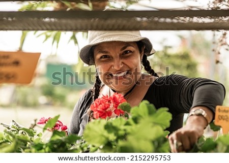 Short, heavy-set Latina woman working in her botanical garden with a hat on her head, very happy. Royalty-Free Stock Photo #2152295753