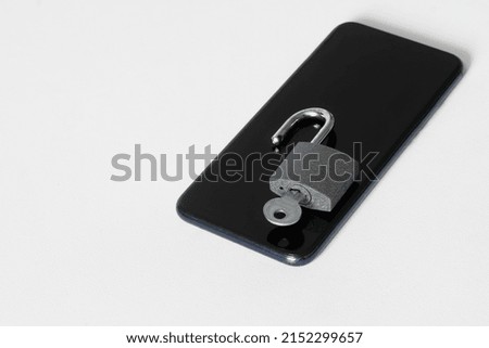 Modern mobile phone and open padlock with key on white background. Concept of cracking password on smartphone. Problem of protecting digital information. Copy space. White background. Close-up