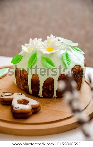 Vertical shot of an Easter bunny cookie and Ukrainian Easter bread (Paska Easter bread) on a round wooden plate