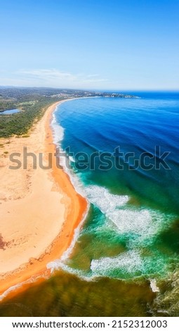 Long curved line of sandy Tathra beach on Sapphire coast of Australian pacific - vertical aerial seascape panorama. Royalty-Free Stock Photo #2152312003