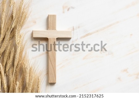 Wood cross with border of ears of wheat on a white wood background with copy space