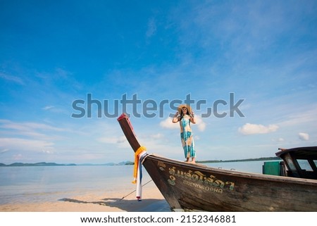 Women wearing  dresses, sitting on wooden boat wearing the hat with beautiful blue sky view of Koh Yao, Phang-nga , Thailand, non English words  shown in this picture is the name of boat  Seangsopha