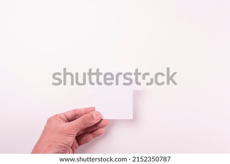 top view of  holding cutout white paper plain house by fingers on white paper background in concept of business banking and insurance.