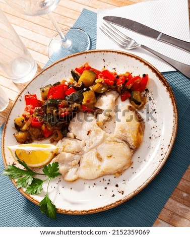 Scandinavian cuisine seafood served with fried vegetables on plate on wooden table