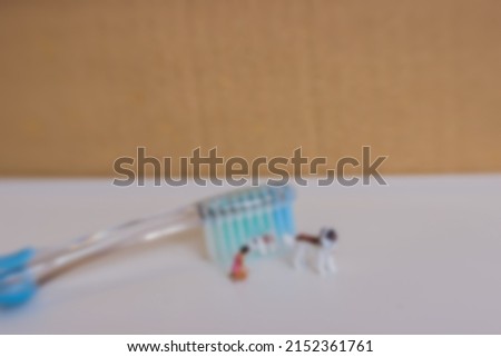 gaussian blur image of miniature dog and people with tooth brush