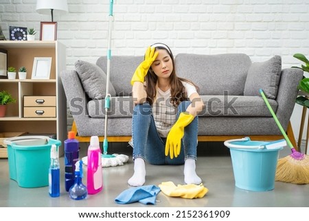 Beautiful Asian housewife feeling tired after doing housework. She sits on the floor in the living room with home cleaning products. Royalty-Free Stock Photo #2152361909