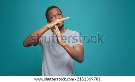 Serious tired person advertising timeout symbol with hands, doing t shape sign to express half time and break. Exhausted man refusing to work, declining and ingoring control. Stop gesture. Royalty-Free Stock Photo #2152369781