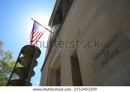 US Department of Justice building under the national flag of the United States on a sunny day, Washington DC, United States