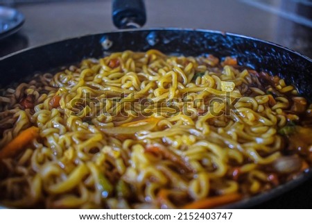 Stock photo of delicious homemade hot and spicy noodles with vegetables,spices and herbs kept in frying pan. Picture captured under natural light at Bangalore, Karnataka, India. focus on object.