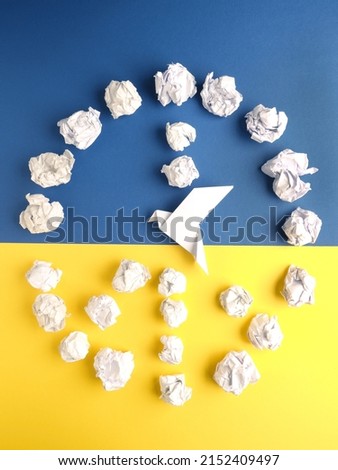 Peace symbol of crumpled paper balls with an origami dove on blue and yellow paper as Ukrainian flag
