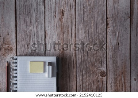 Notebook with pen, notes and USB flash drive on wooden background. Top view. Copy space. Selective focus.