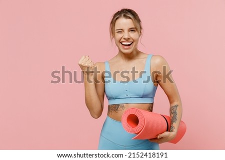 Young strong sporty athletic fitness trainer instructor woman wear blue tracksuit spend time in home gym do winner gesture clench fist isolated on pastel plain pink background. Workout sport concept Royalty-Free Stock Photo #2152418191