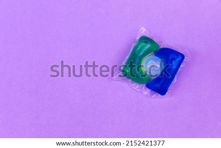 Laundry capsules of clothes for the washing machine with detergent on a lilac background. View from above. Space for copy.Cleanliness concept.