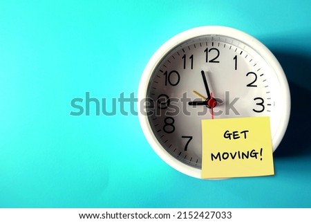 Wall clock on blue copy space background with handwritten note GET MOVING!, concept of having difficulty setting aside exercise time, reminder for health improvement by being more physically active Royalty-Free Stock Photo #2152427033