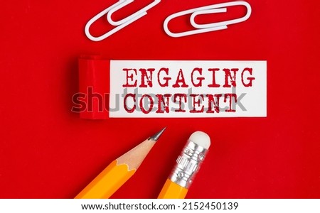 ENGAGING CONTENT message written on a torn red paper with pencils and clips, business