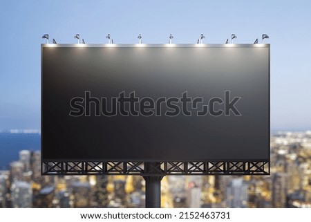 Blank black billboard on cityscape background at evening, front view. Mock up, advertising concept