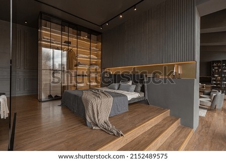 bedroom and freestanding bath behind a glass partition in a chic expensive interior of a luxury home with a dark modern design with wood trim and led light Royalty-Free Stock Photo #2152489575