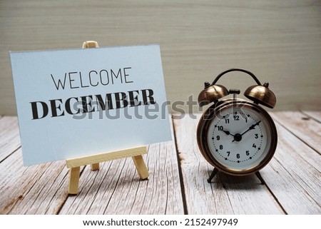 Welcome December text message with alarm clock on wooden background