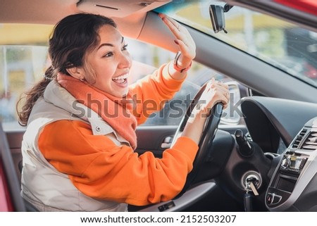 Polite woman driver raised her hand as a sign of respect and says thank you for giving way. Relations between people in traffic regulations Royalty-Free Stock Photo #2152503207