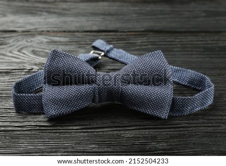 Stylish blue bow tie on black wooden background, closeup