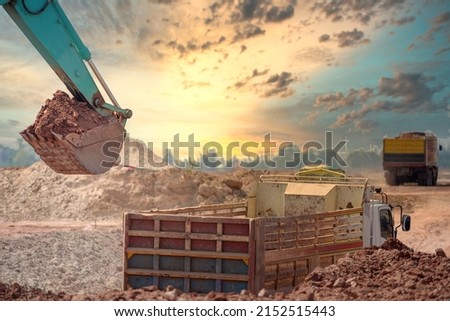 Close-up photo of excavator at a construction site A crawler excavator is shoveling soil into a large dump truck or trailer. The backhoe works by digging the soil at the construction site.