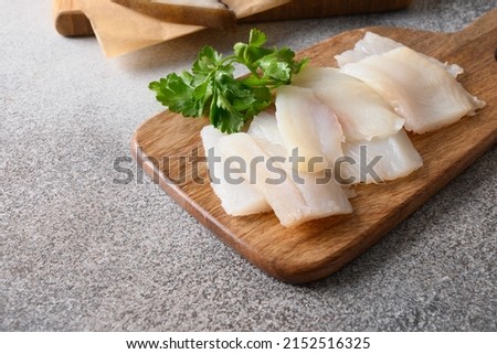 Delicacy fish smoked halibut served with parsley for eating on wooden cutting board. Close up. Rich of healthy omega 3 unsaturated fats.