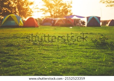 Selective focused on Lawn or green grass ground of camping ground near the sea beach. with camping tent in the background.
