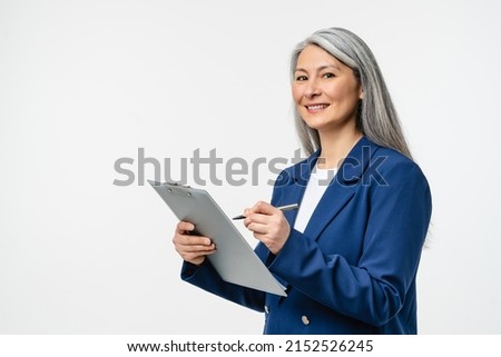 Female mature auditor inspector examiner controller in formal wear writing on clipboard, checking the quality of goods and service looking at camera isolated in white background Royalty-Free Stock Photo #2152526245
