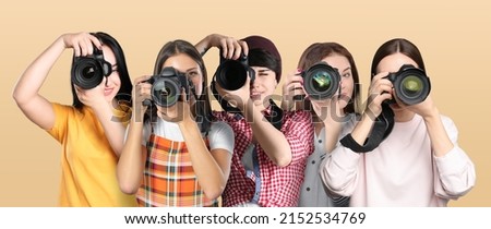 Group of professional photographers with cameras on beige background. Banner design