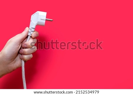 Electric plug for a socket on a red background. The concept of electricity and its importance in everyday life. Electric plug without socket. Free space for text Royalty-Free Stock Photo #2152534979