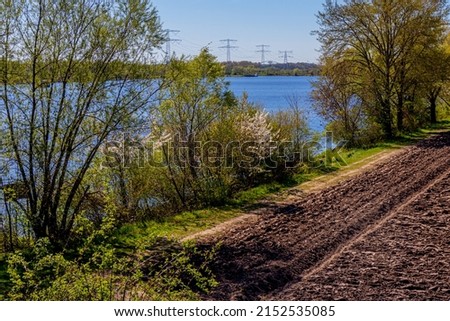 Aerial view of farmland prepared for cultivation, uncultivated along a trail with trees, wild plants and the Oude Maas river, sunny spring day in Stevensweert, South Limburg, Netherlands Royalty-Free Stock Photo #2152535085