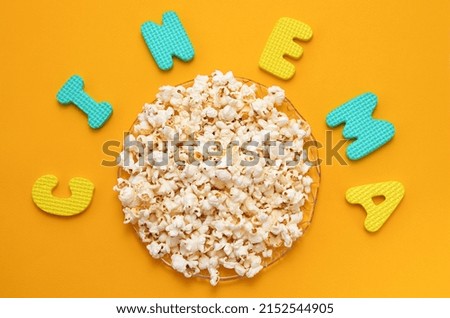 a plate of popcorn on a yellow background and inscription cinema