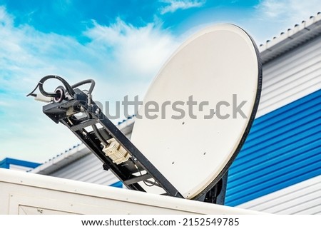 Mobile circular satellite dish is directed at sky. Deployment of communications equipment. Background
