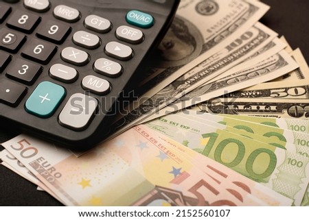 dollar and euro banknotes with calculator on black background