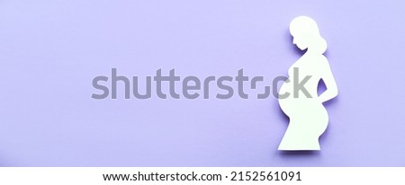 Paper silhouette of a pregnant woman casts a shadow on a lavender background. Flat lay,Banner, place for text. Concept of pregnancy.