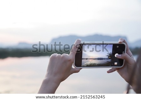girl using smartphome taking nature photo and mountain in evening time. low light image with selective focus.