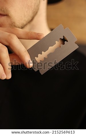 man's hand holding empty business card in the form of a blade for beauty salon, barbershop. stylish free blank copy space. . High quality photo.