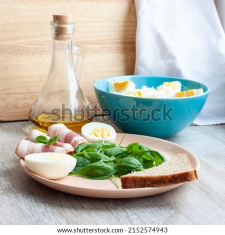 Food. Healthy breakfast. Plate with spinach leaves, green basil, bacon, eggs and a piece of rye bread. Salad of cabbage and eggs. Fragrant spicy olive oil with pepper. Selective focus