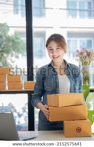 Young businesswoman in Asia packs products in cardboard boxes and sends customers work from home with laptops to take orders. small business owner start online marketing sme independent business idea
