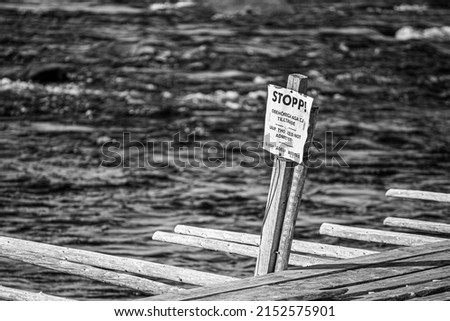 A grayscale shot of the sign on the dock saying stop 