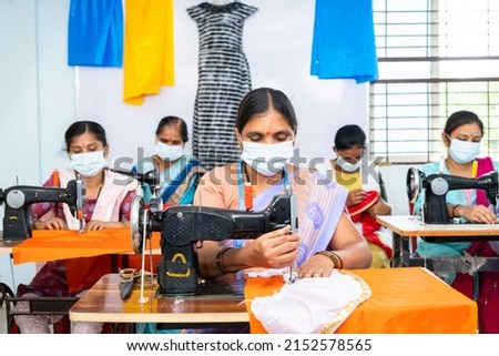 group of garments workers in medical face mask buys working at garments on sawing to protect from coronavirus or covid-19 outbreak - concept of social distance, back to work and safety Royalty-Free Stock Photo #2152578565